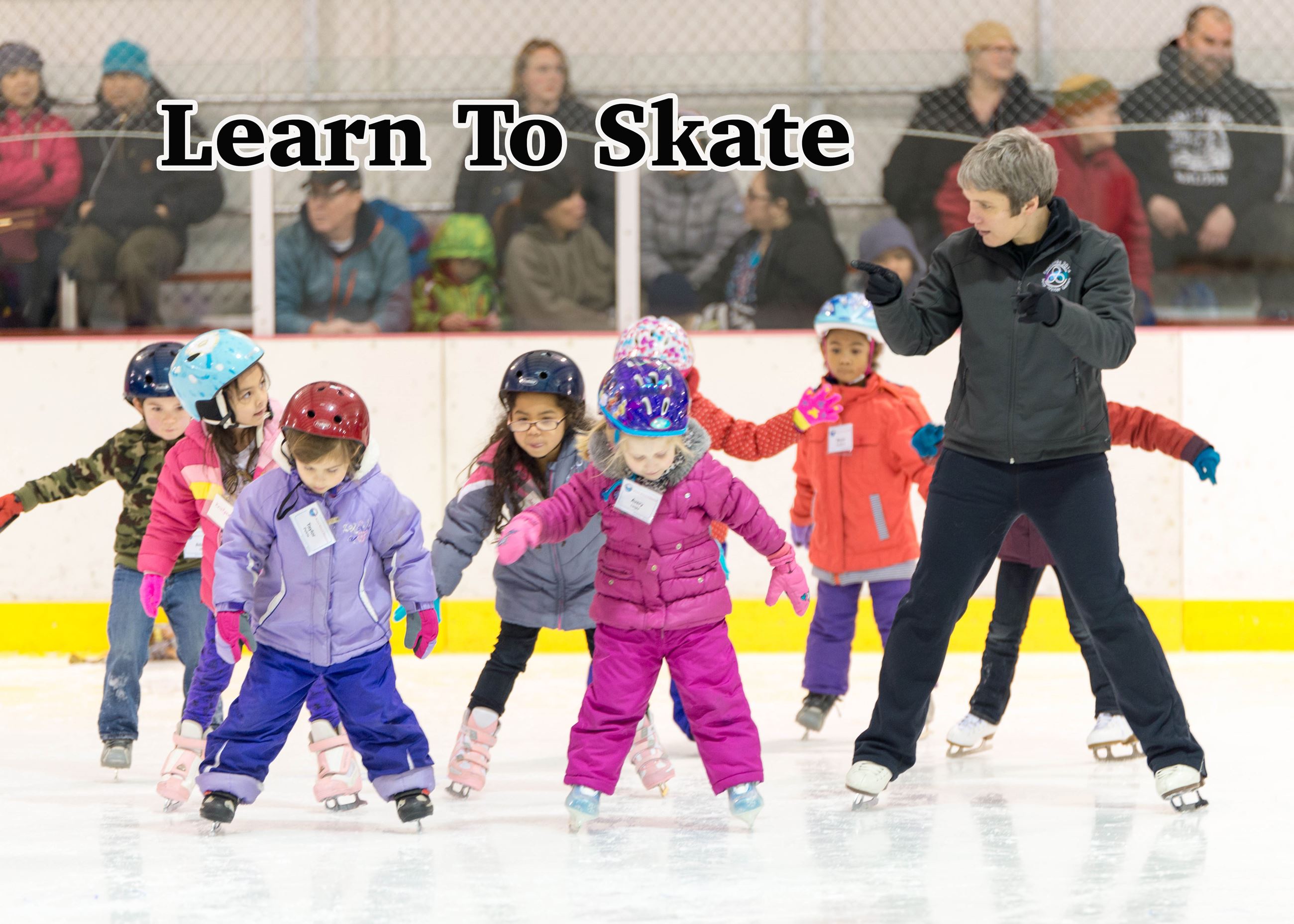 Kids learning to skate with an instructor. 