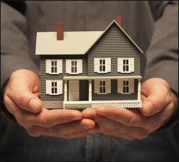 Stock image of a man holding a small home.