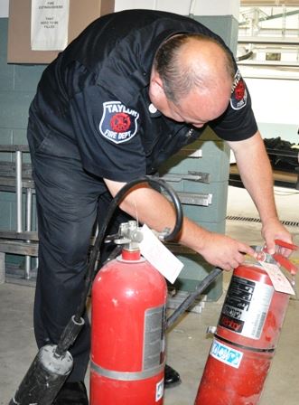 Fire Fighter Checking Gauges on Fire Extinguishers. 