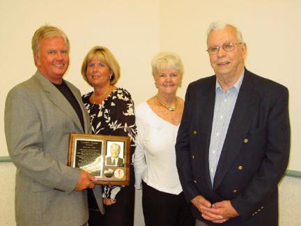 Cameron Priebe with a group of people posing with a plaque.