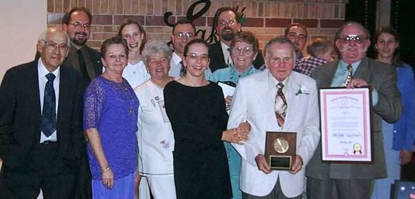 Ernest Molnar and a group of people standing with a man holding a plaque.