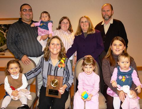 Milissa Hool holding a plaque sitting with a group of people.