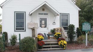 A small white building with flowers in front of it.